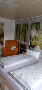 Plaue清晨飞鸟公寓的配有两张床铺的客房,配有橙色椅子和窗户
