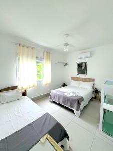 瓜鲁雅Pousada Village Cozumel的白色的客房设有两张床和窗户。