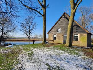 Hooge ZwaluwePicturesque Holiday Home in Drimmelen with Garden的一座两棵树的老房子,毗邻湖泊