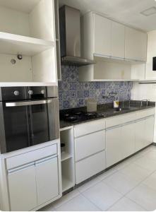 里约热内卢Apê na Gávea的厨房配有白色橱柜和炉灶烤箱。