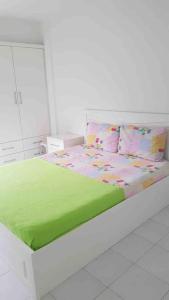 库萨达斯Güzelçamli, Kusadasi Apartment with a pool的白色卧室配有带绿色床单和枕头的床