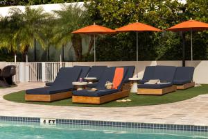 迈阿密海滩Sonder 17WEST的一组椅子和遮阳伞,位于游泳池旁