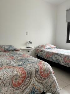 卢汉德库约Complejo Carrodilla - Lujan de Cuyo的酒店客房设有两张床和一张桌子。