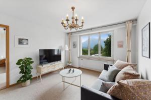 图恩湖畔上霍芬Lakeview apartment in beautiful Oberhofen的带沙发、电视和桌子的客厅