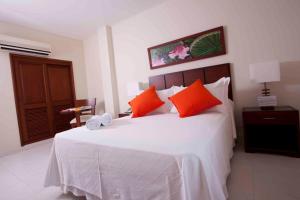 莱蒂西亚Hotel Anaconda的卧室配有带橙色枕头的大型白色床