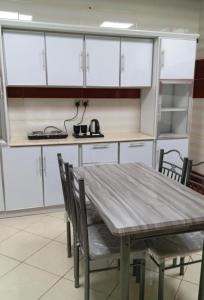 麦地那Al Asar almasi Suite Apartments的厨房配有白色橱柜和桌椅