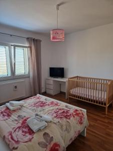 RadošinovacHouse Iva Luca的一间卧室配有一张床、一张婴儿床和一台电视。