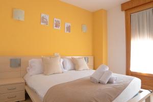 锡古恩萨Hostal-Casa Rural Rosa-Nonna的一间卧室拥有黄色的墙壁,配有一张带白色枕头的床。