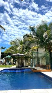 瓜鲁雅Pousada Village Cozumel的一座种植了棕榈树的大型蓝色游泳池,位于一座房子旁边