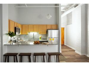 印第安纳波利斯Modern Apartment Close To Everything CozySuites的厨房配有木制橱柜和带凳子的台面