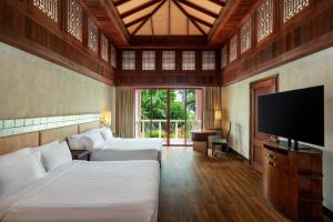 卡伦海滩Centara Grand Beach Resort Phuket - SHA Plus的一间卧室配有两张床和一台平面电视