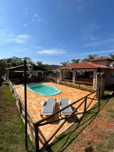 瓜佩Pousada Estância Mineira的一个带两把椅子的庭院和一个游泳池