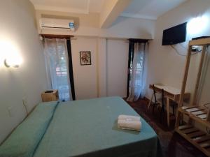 布宜诺斯艾利斯Hotel Manzanares Plaza的一间卧室设有一张绿色的床、一张书桌和窗户。