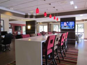 迈尔斯堡I-75迈尔斯堡机场汉普顿酒店的餐厅设有酒吧、粉红色的椅子和电视
