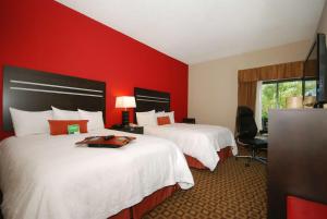 迈尔斯堡I-75迈尔斯堡机场汉普顿酒店的红色墙壁的酒店客房内的两张床