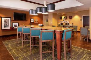 格林斯伯勒格林斯博罗机场希尔顿恒庭酒店的一个大厨房,有一个大岛,上面有蓝色的酒吧凳子