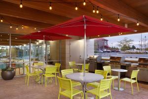 爱达荷福尔斯爱达荷福尔斯希尔顿欣庭套房酒店的餐厅设有桌子、黄色椅子和红色遮阳伞