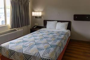 拉夫金Motel 6-Lufkin, TX的酒店客房,配有一张带色彩缤纷的被子的床