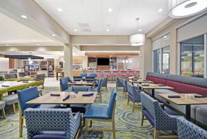 休斯顿Hilton Garden Inn Houston Hobby Airport的一间配备有桌子和蓝色椅子的用餐室