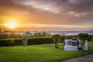 维雷亚阿斯顿毛伊岛山酒店的庭院内的烧烤架,背景是日落