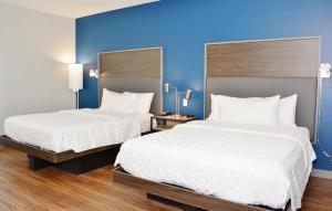 大章克申Tru By Hilton Grand Junction Downtown的两张位于酒店客房的床,拥有蓝色的墙壁
