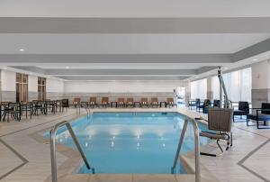 爱迪生Homewood Suites By Hilton Edison Woodbridge, NJ的酒店大堂的游泳池,配有桌椅