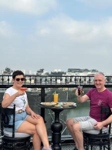 河内Scent Premium Hotel的两人坐在桌子旁,一边享用食物和饮料