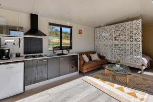 旺阿雷Valley View - Whangarei Tiny Home的厨房以及带沙发和桌子的客厅。
