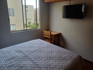 利马Habitación acogedora Orué的一间卧室配有一张床、一台电视和一张书桌