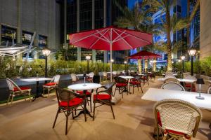多哈Le Méridien City Center Doha的一间带桌椅和红伞的餐厅