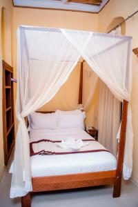 NgamboThe Island Stone Town hotel的一间卧室配有一张带天蓬的床