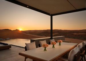 拉斯阿尔卡麦拉斯阿尔卡麦山谷沙漠丽思卡尔顿酒店的一张桌子和椅子,享有沙漠的日落美景