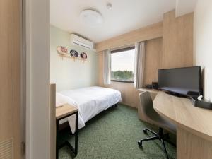 成田Tabino Hotel EXpress Narita的酒店客房设有一张床、一张书桌和一台电视机。