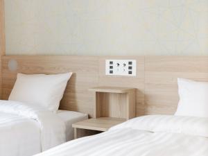 成田Tabino Hotel EXpress Narita的两张带白色床单的床和床头柜