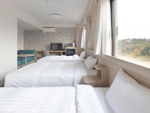 成田Tabino Hotel EXpress Narita的酒店客房设有三张床和窗户。