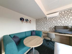 成田Tabino Hotel EXpress Narita的客厅配有蓝色的沙发和桌子