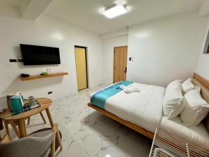 长滩岛LuckyTito Dmall Boracay的一间卧室配有一张床、一张桌子和一台电视。
