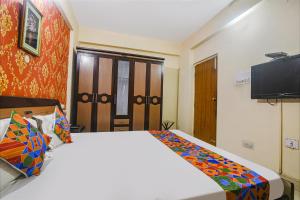 巴特那FabHotel Maadhavam Residence的一间卧室配有一张大床和电视