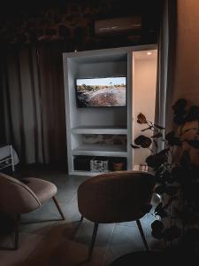 沃丽曼村Vigla Villas的客厅配有2把椅子和平面电视