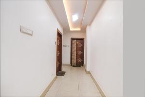 巴特那FabHotel Raj Niwas的走廊上设有白色的墙壁和门,铺有瓷砖地板