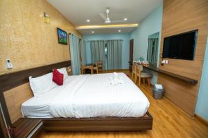 巴拉特布尔Diyalo Foodland Chitwan的卧室配有一张白色大床和一台平面电视。