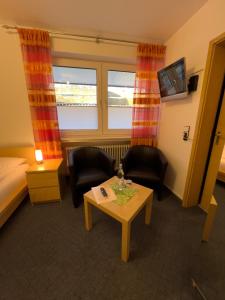 维林根Hotel Haus Christel的酒店客房带一张床、一张桌子和椅子