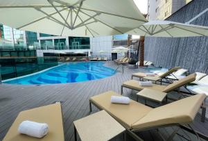 迪拜Al Khoory Sky Garden Hotel的一个带桌椅和遮阳伞的游泳池