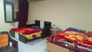 巴德里纳特Badrinath Jbk by Prithvi Yatra Hotel的一间卧室配有两张床和一张桌子