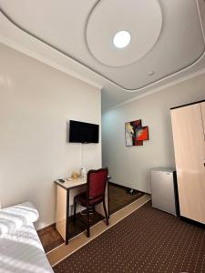 努库斯HOTEL ARAL的酒店客房设有一张桌子、一张床和一台电脑
