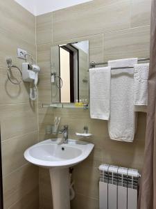 努库斯HOTEL ARAL的浴室配有盥洗盆、镜子和毛巾