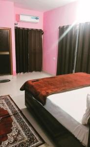 AyodhyaPremshi Guest House的卧室配有一张带粉红色墙壁的大床