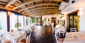 切法卢凯拉尼卡度假酒店的餐厅设有白色的桌椅和窗户。
