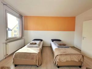 菲林根-施文宁根Cozy Vacations Home in the Black Forest的橙色墙壁的客房内的两张床
