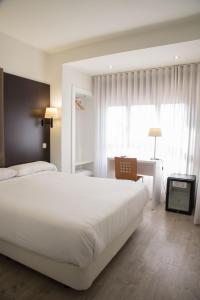 图德拉德尔塔酒店的卧室配有白色的床、书桌和窗户。